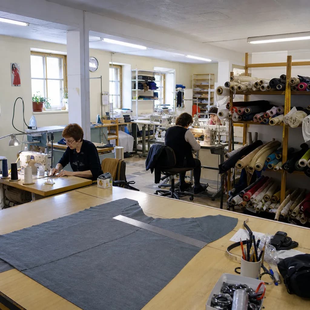 A small European garment atelier, with fabric rolls, cutting tables and sewing stations